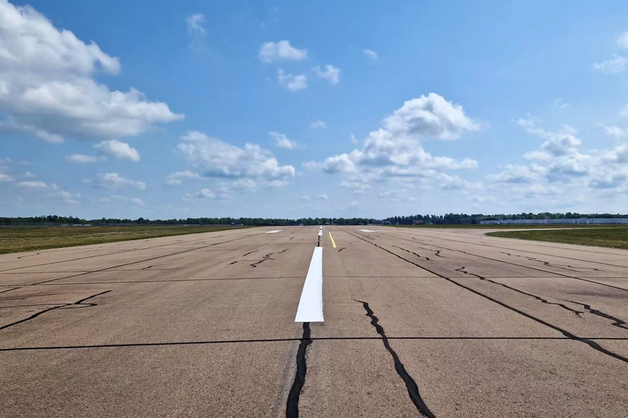 Foto av tom landningsbana på flygfält en solig dag.